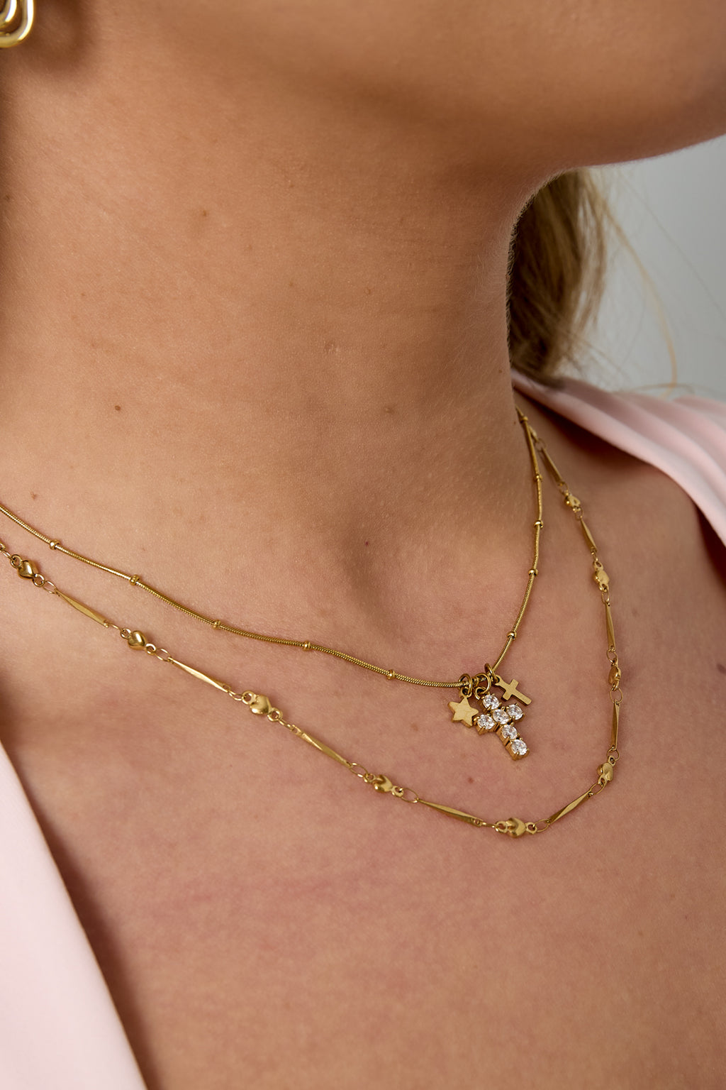 Ketting met kruis- en sterbedeltjes - goud - gedragen om de hals van een model