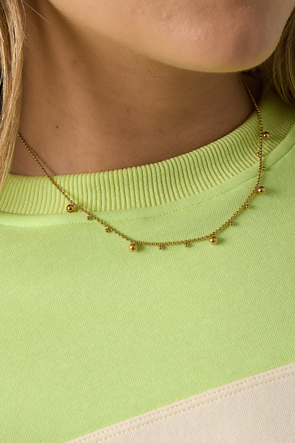Ketting met afwisselende bolletjes - goud - gedragen om de hals van een model ingezoomd