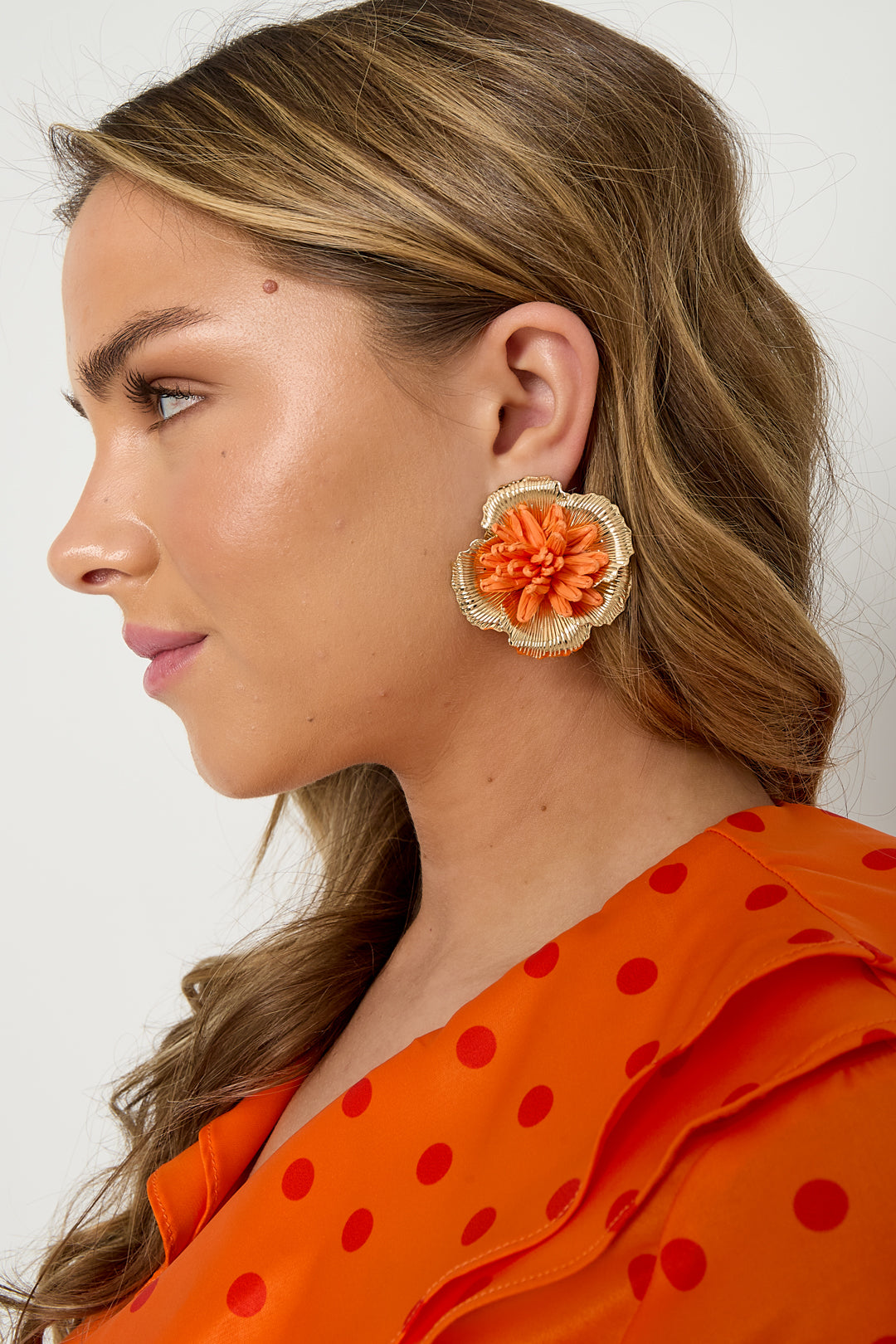 Oorbellen met 3D rafia bloem - oranje - gedragen in het oor van een model zijaanzicht