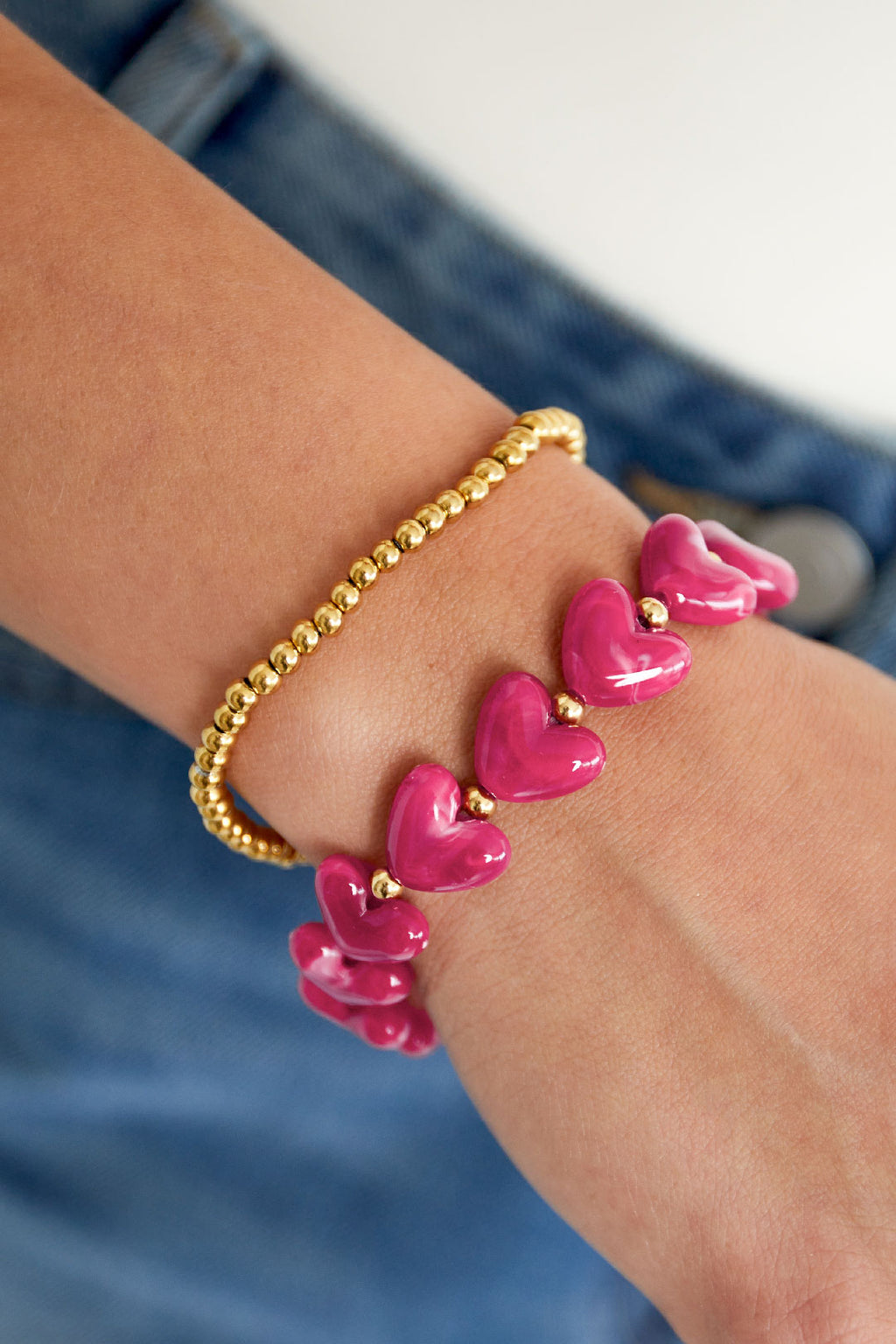 Elastische armband met hartkralen - roze - gedragen om de arm van een model