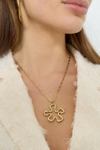 Ketting met hangende bloemcharm - goud - gedragen om de hals van een model ingezoomd 